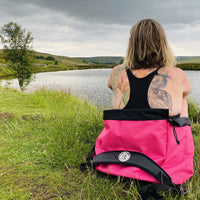 Woman sitting in her pink Terrapin Swim Feral bag looking out across the water