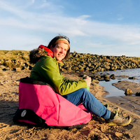 Woman sitting in a pink Turtleback outdoor swimming bag